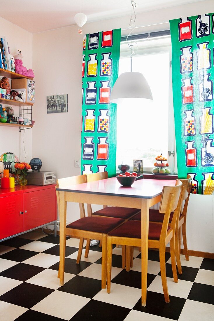 Esstisch in Küche mit Schachbrettmusterboden & bunten Fenstervorhängen