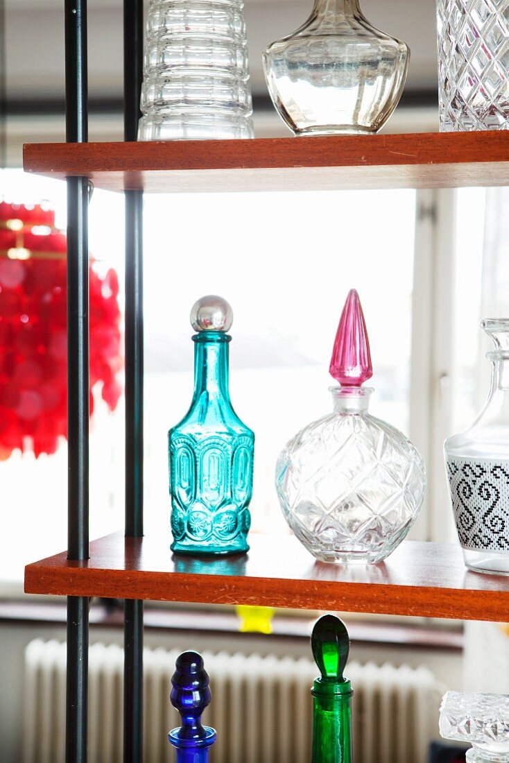 Decorative glass bottles of various shapes & colours on open shelving