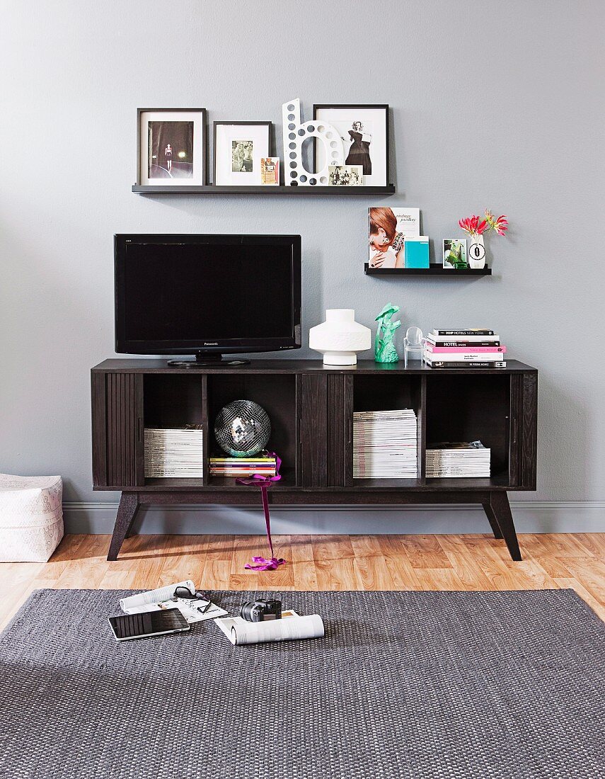 TV on retro-style media cabinet below pictures on narrow floating shelves