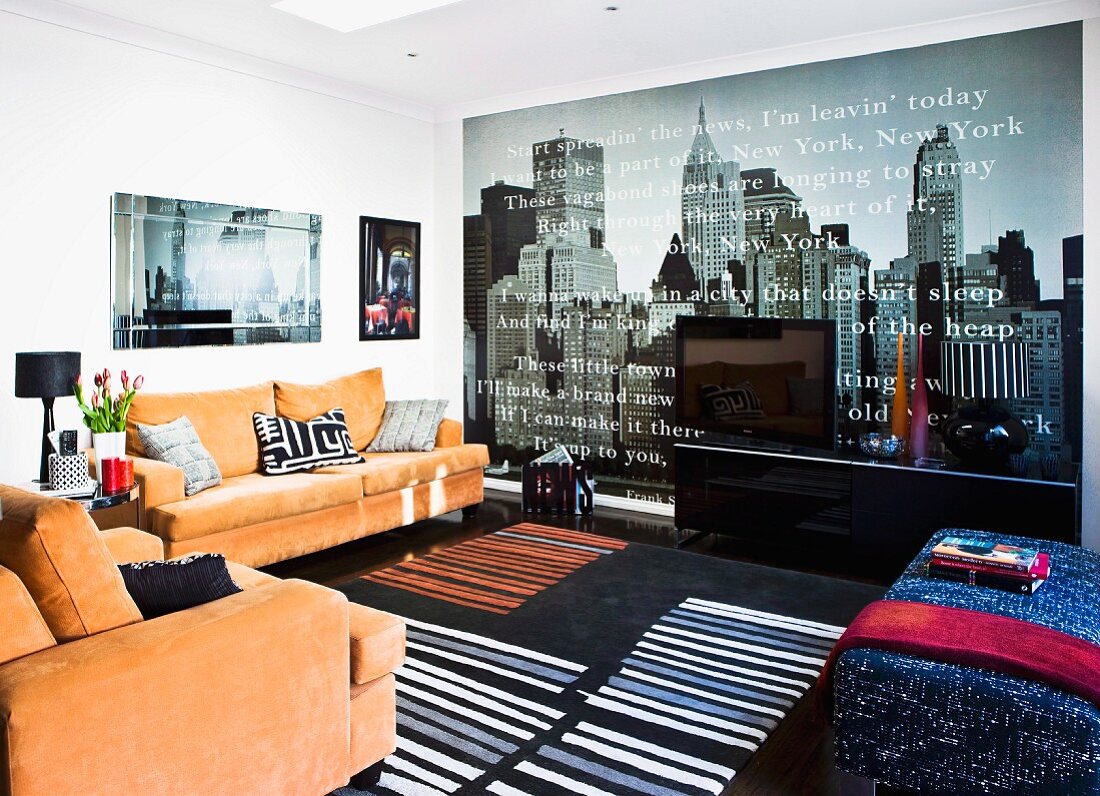 Bright, modern living room with skylight, photo wallpaper of New York skyline and orange sofa set