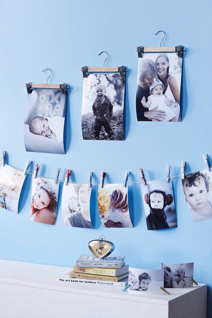 Mit Mini-Wäscheklammern an einer Schnur befestigte Familienfotos und Fotos an kleinen Kleiderbügeln