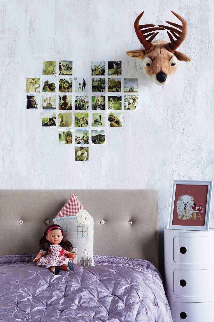 Herzförmig an die Wand geklebte Familienfotos neben lustiger Tiertrophäe