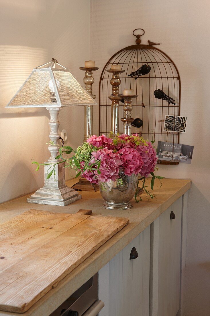Shabby Dekoration mit Hortensienstrauss und stilisiertem Vogelkäfig auf rustikaler Küchenzeile