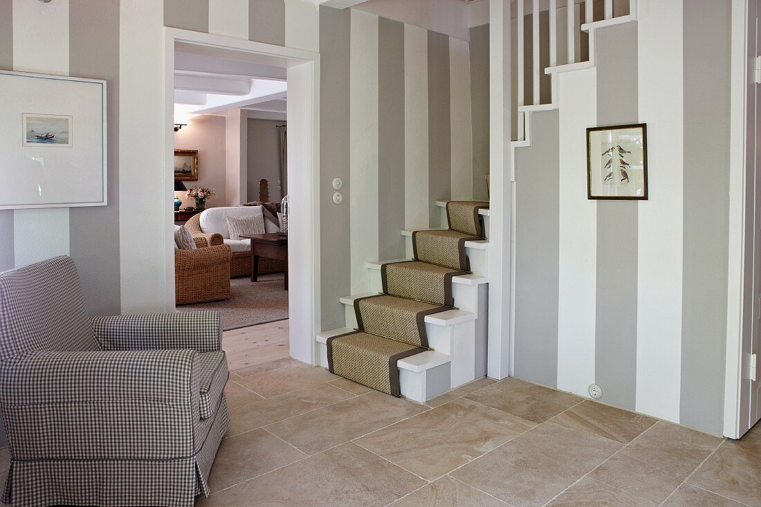 Walls with wide stripes and stone flags in classic foyer with foot of stairs