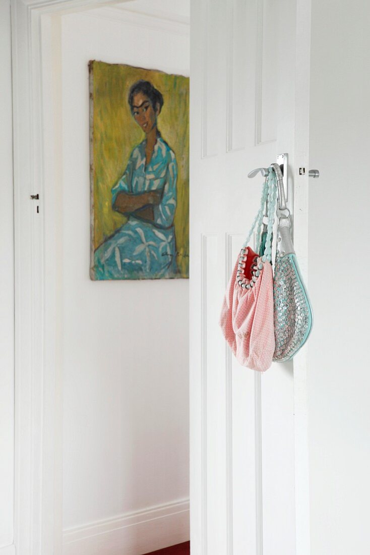 Vintage handbags on handle of traditional interior door and picture on wall in background