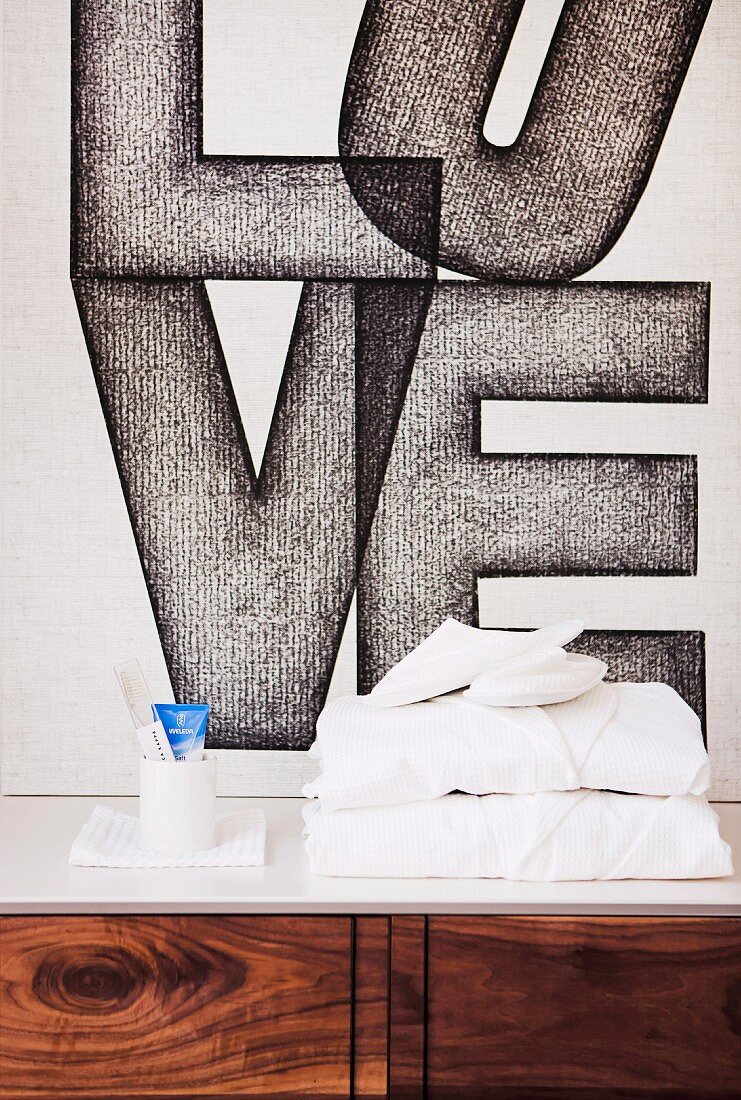 Modern mural of the word 'Love' behind stacked towels and toiletries