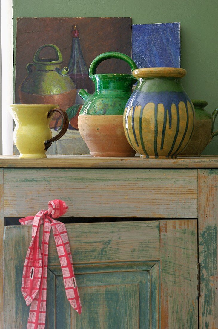 Painted ceramic vessels on vintage wooden cabinet
