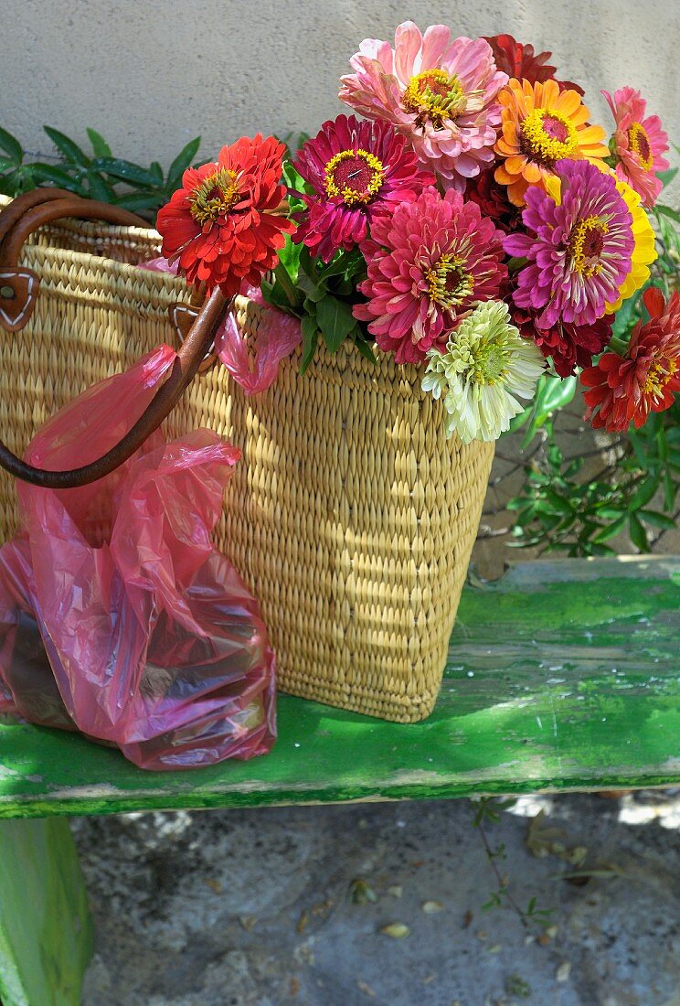 Bunter Blumenstrauss in Einkaufstasche aus Geflecht auf Vintage Holzablage