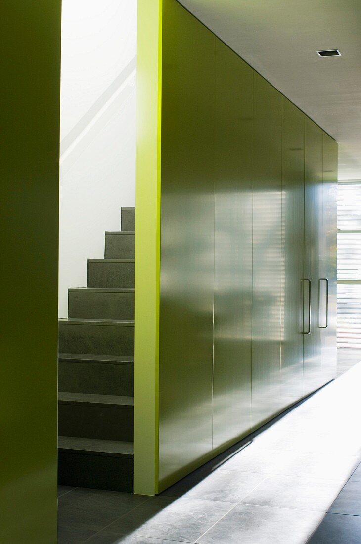 Staircase hidden behind yellow wall with integrated cupboards