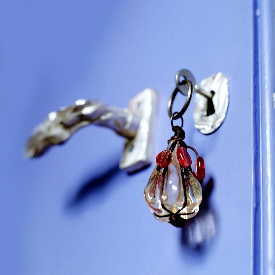 Schlüssel mit Glasanhänger an lila Zimmertür