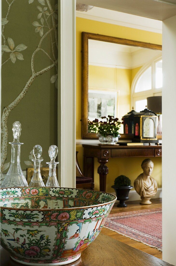 Kostbare Porzellanschale und Kristallkaraffen neben geöffneter Tür mit Blick auf dekorierten Konsolentisch
