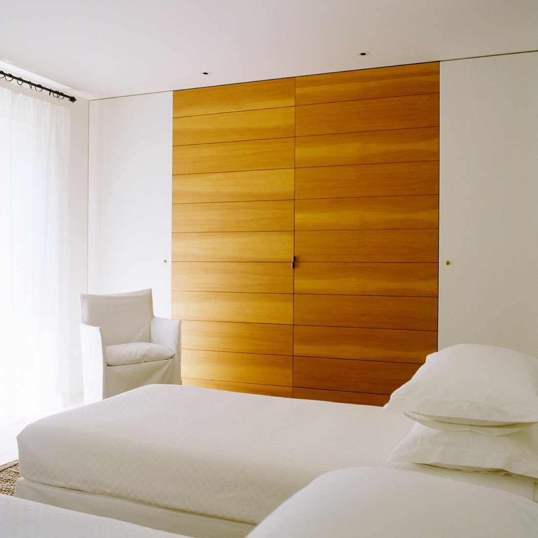 Eingebauter Schlafzimmerschrank mit interessantem Kontrast durch seitlich unauffällig weiße Türen und massgefertigte Holzelemente
