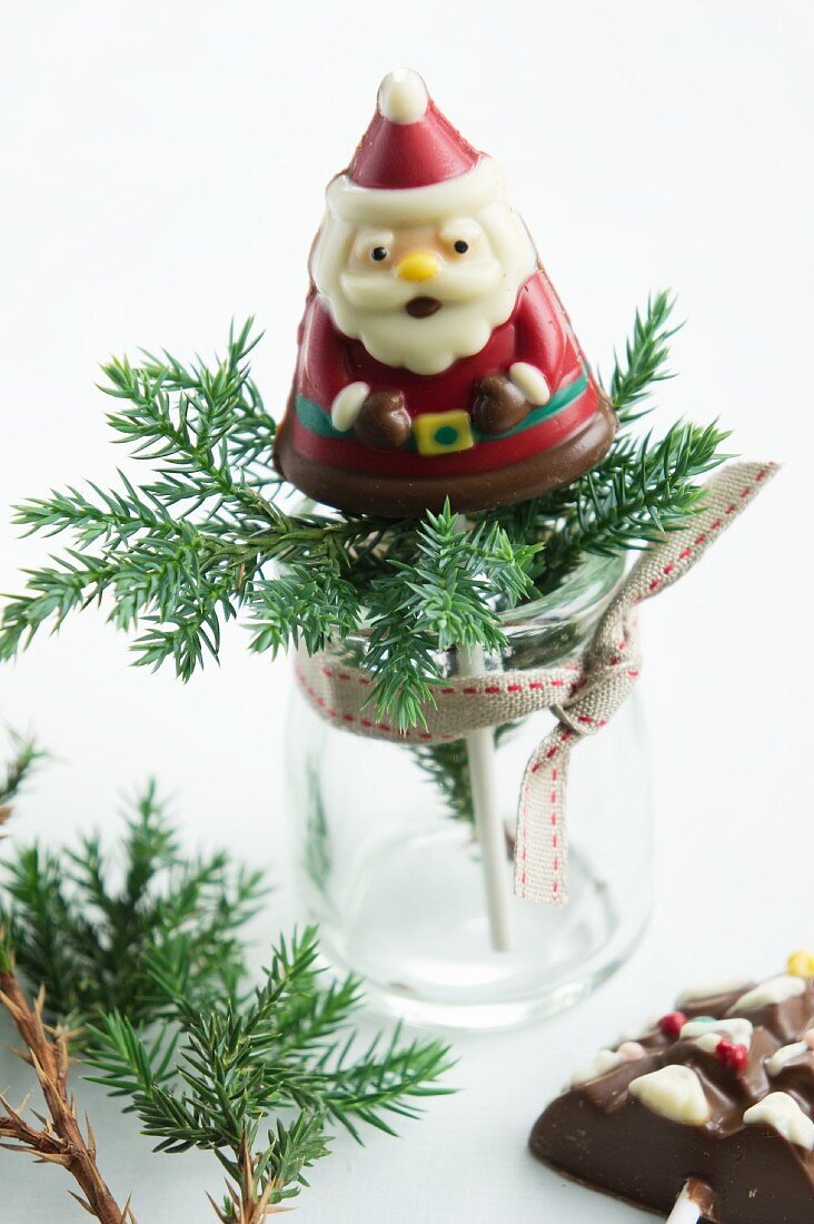 Nikolaus aus Schokolade auf Stöckchen und Koniferenzweig im Glas