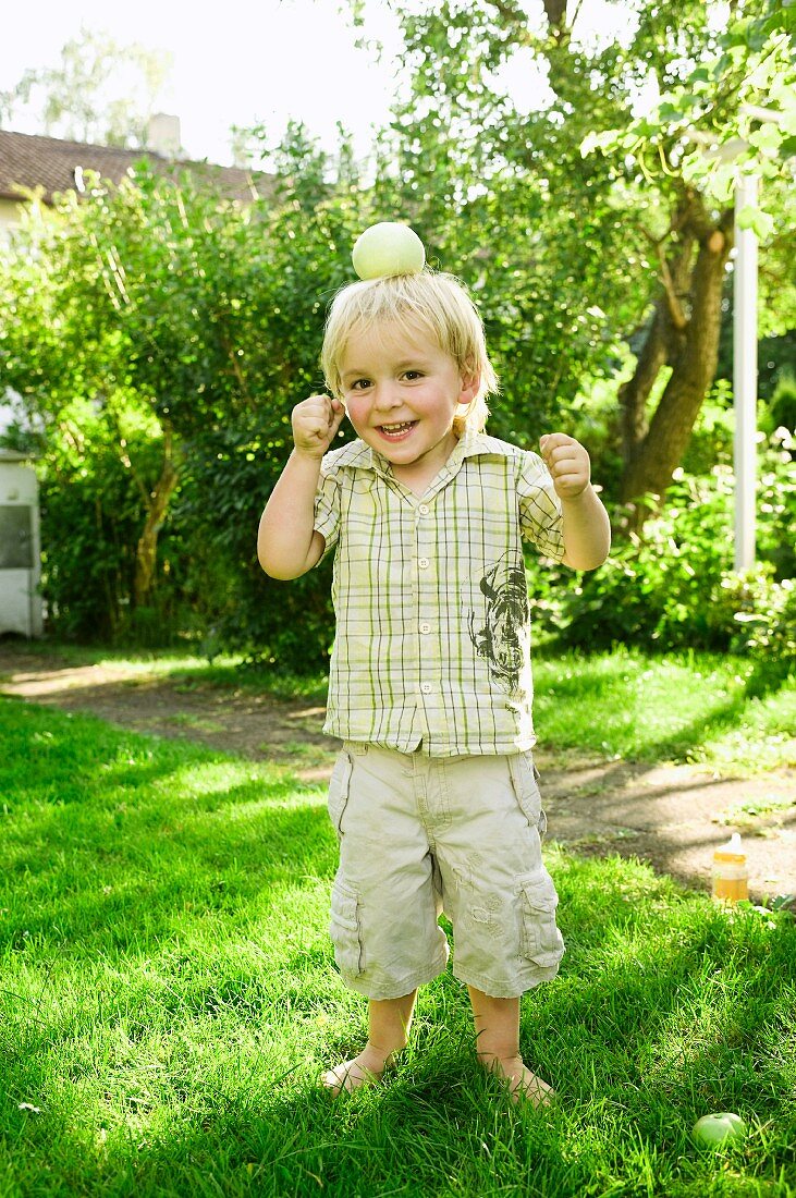 Junge mit Apfel auf dem Kopf im Garten
