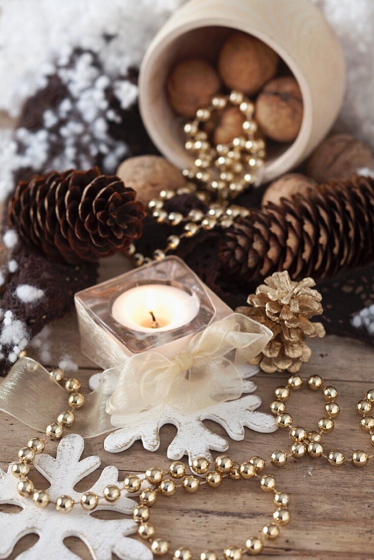 Christmas decorations with pine cones, nuts, string of peals and a tea light
