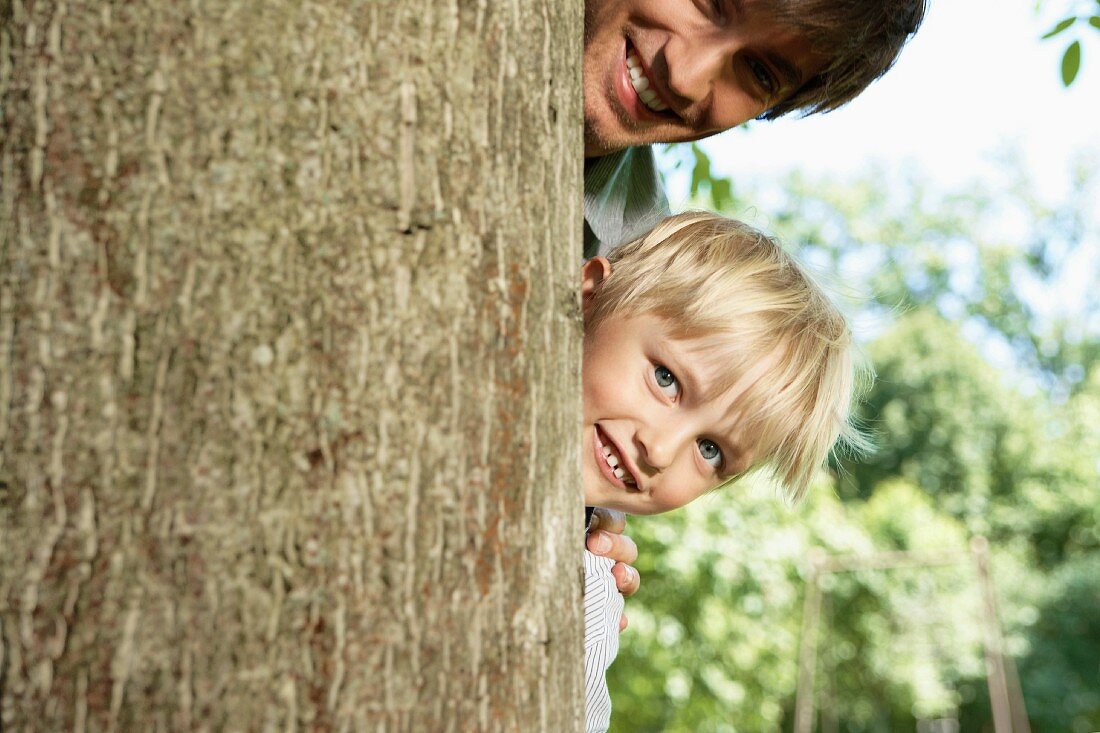Vater und Sohn hinter einem Baum