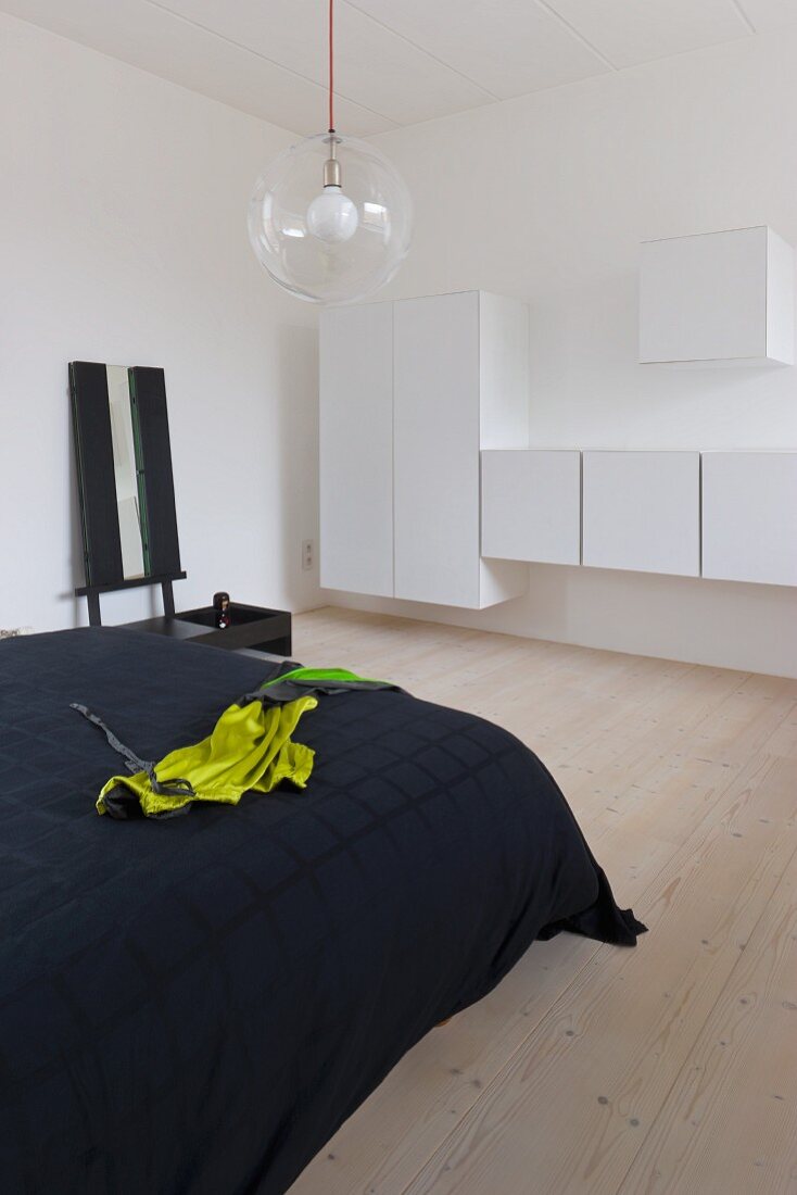 Doppelbett mit schwarzer Tagesdecke und weiße Wandschränke in minimalistischem Schlafzimmer