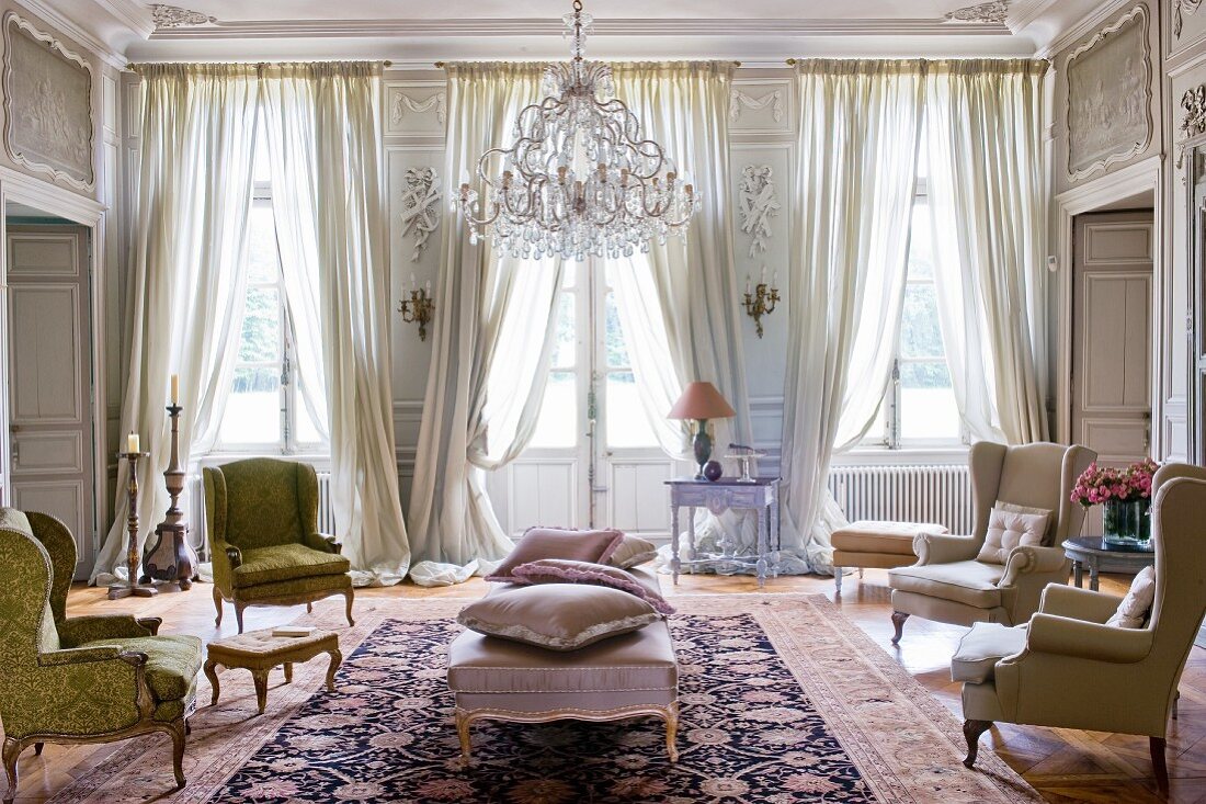 Grand salon with Rococo armchairs and draped curtains on windows and French doors
