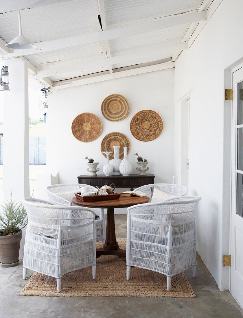 Colonial-style veranda with white rattan chairs and antique wooden table