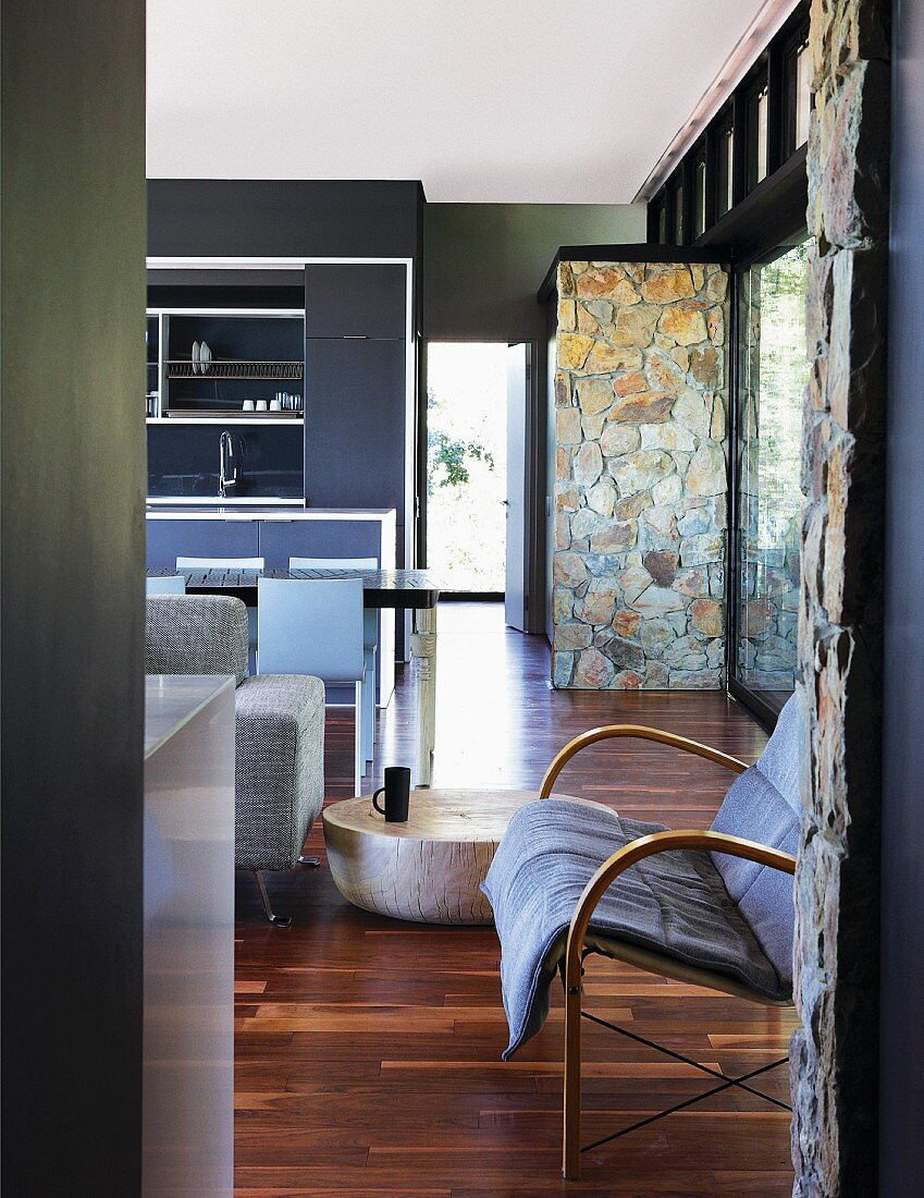 Open-plan interior in subtle shades of grey with rough stone wall contrasting with anthracite-coloured wall