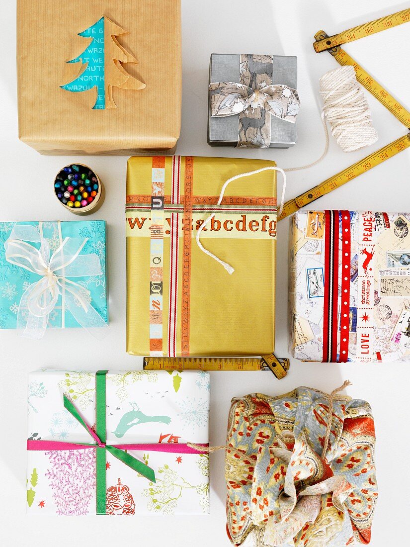Mit Schrift- und Musterbändern oder Scherenschnitt verzierte und mit ungewöhnlich gemusterten Papieren ideenreich gestaltete Weihnachtspäckchen
