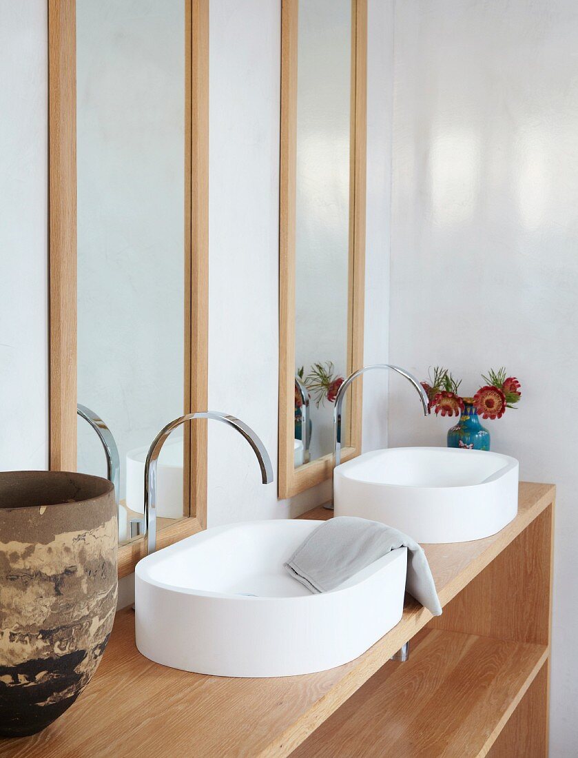 Zwei Waschbecken auf Regal-Unterschrank vor gerahmten Wandspiegeln in Badecke
