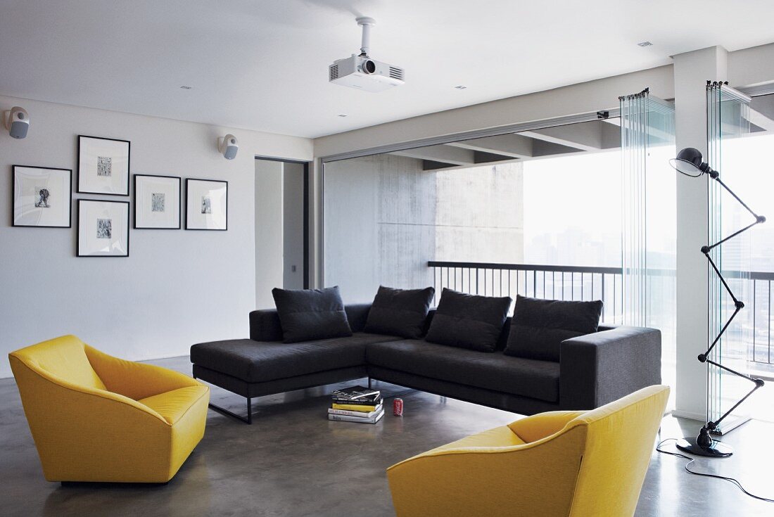 Bright, modern living room with yellow and blue sofa and armchairs; open folding glass doors providing access to balcony