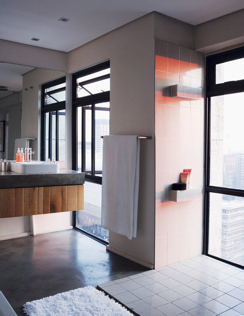 Geräumiges Badezimmer mit raumhohen Fenstern und roten Wandkacheln im Abendlicht