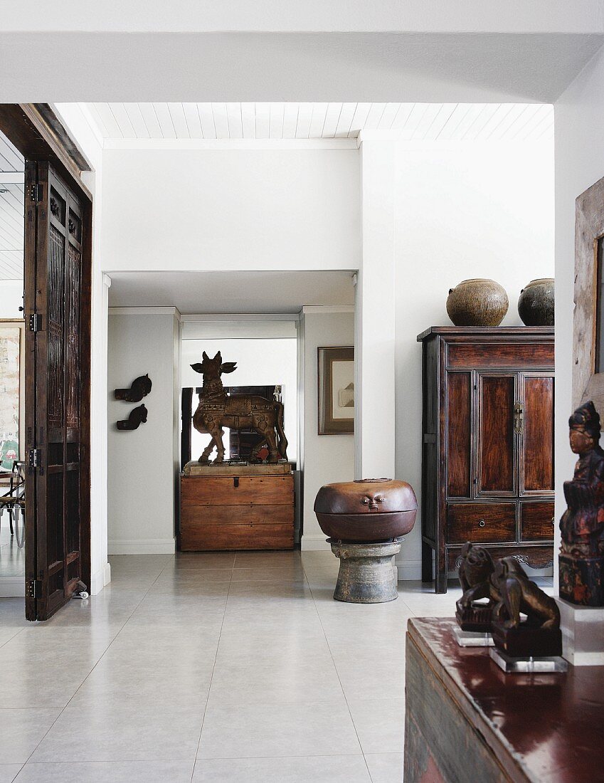 Indian sculpture of the bull Nandi on a rustic wooden trunk in the centre of a bright, spacious interior with antique Chinese furniture and objets d'art from around the world