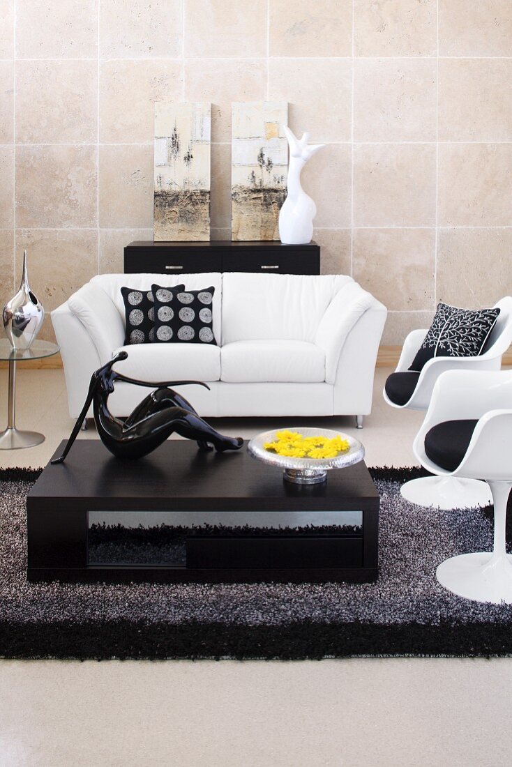 Wohnzimmer mit weisser Ledercouch, Kunstobjekten in Schwarz und Weiß und einem schwarzen Couchtisch