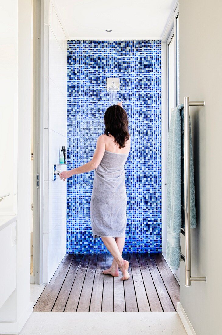 Duschen in hellem Duschraum mit Holzdielenboden und mosaikgefliester Wand