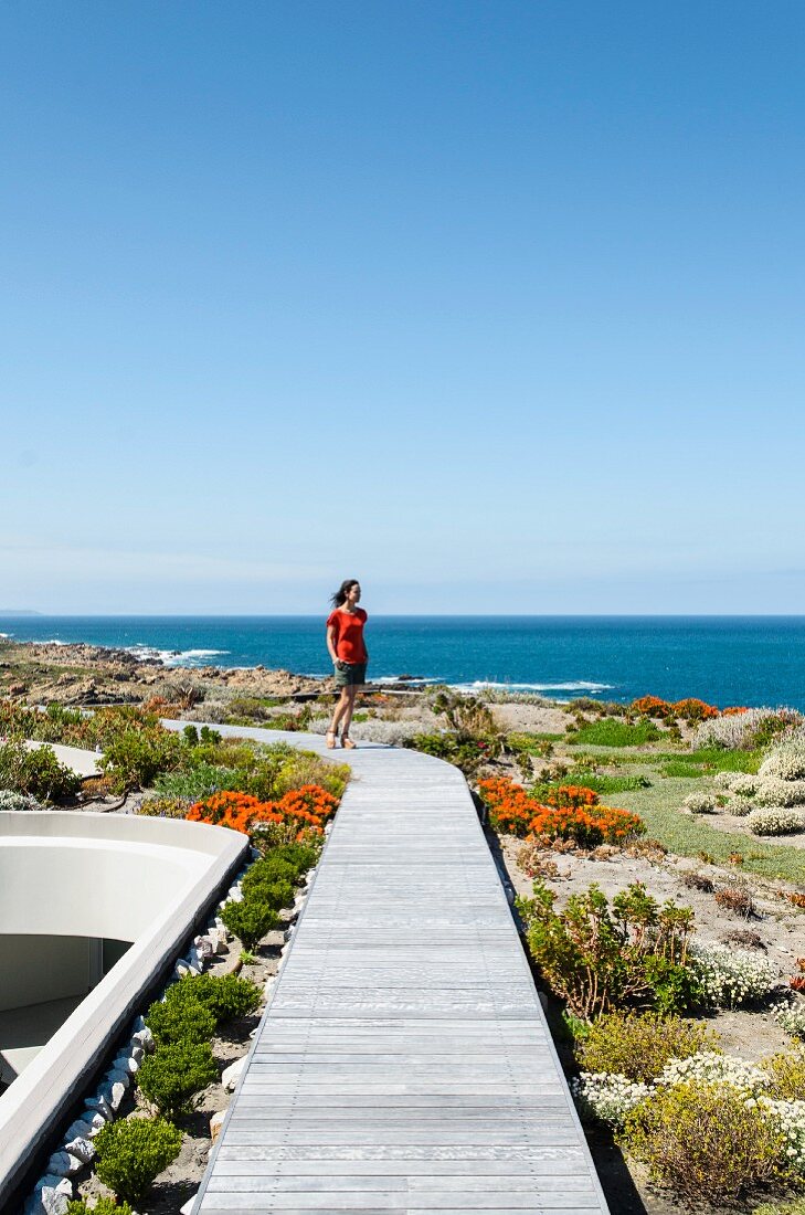 Woman on private wooden walkway in flowering coastal landscape