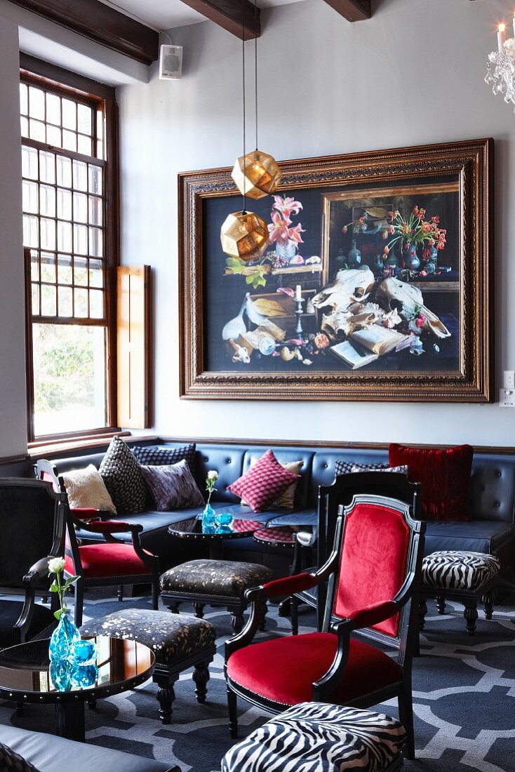 Lounge with large sash window and long leather couch below large painting with massive wooden frame