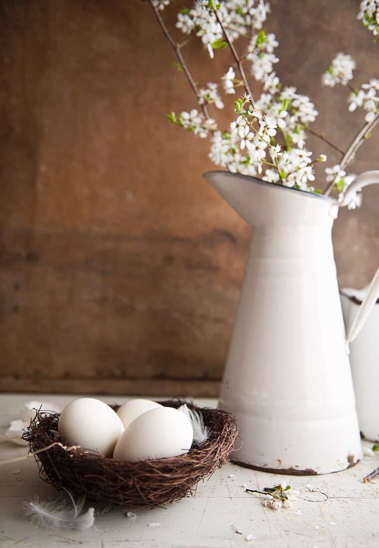 Eggs in a nest and an enamel jug with sprays of flowers