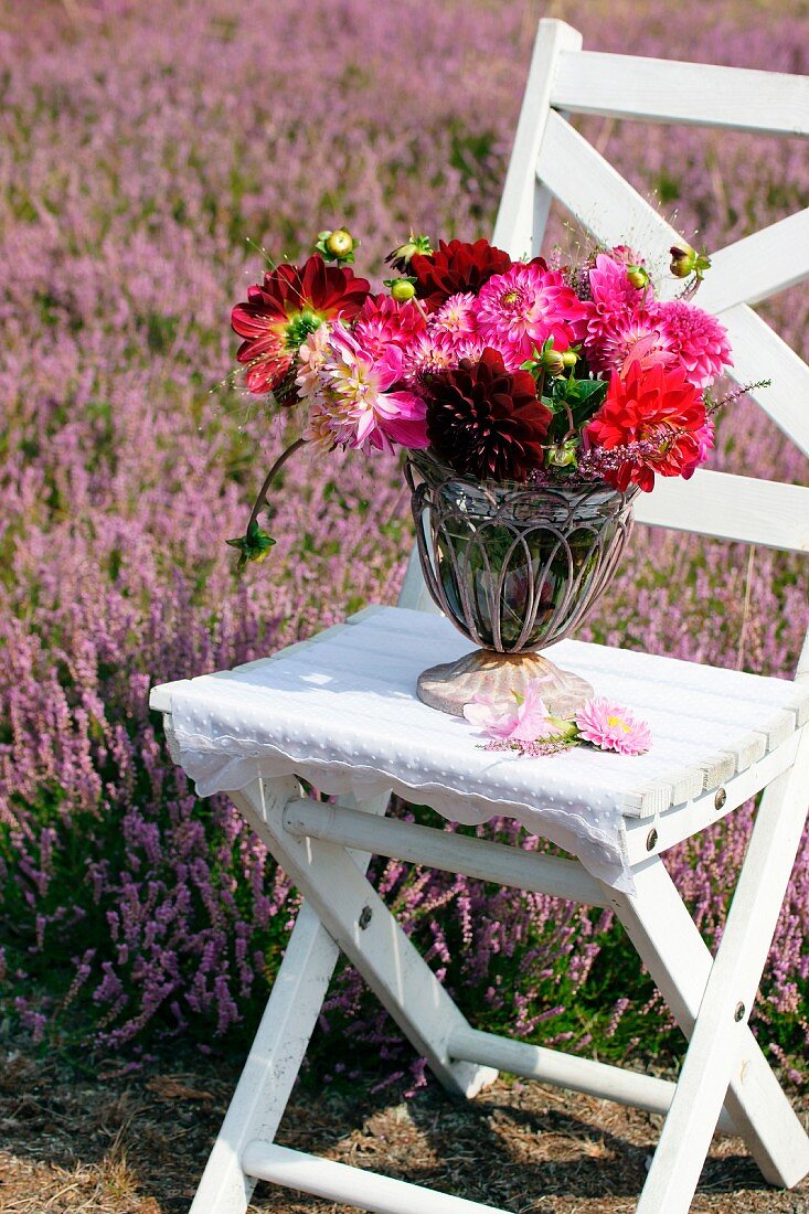 Sommerlicher Blumenstrauss mit Dahlien und Erika auf einem Gartenstuhl