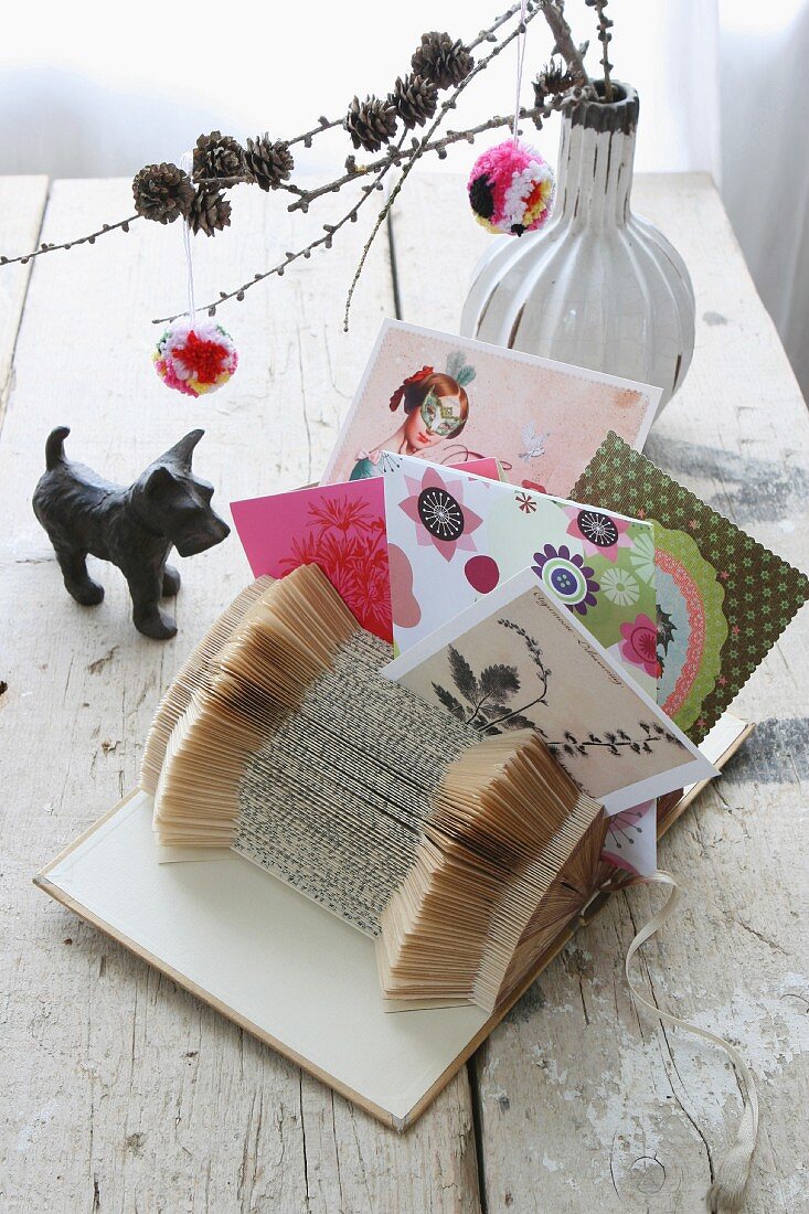 Decoration idea: folded book as postcard stand, pompoms