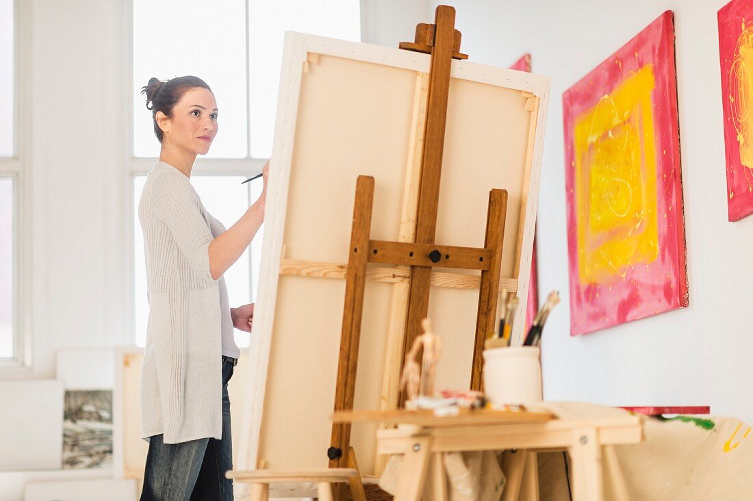 Woman painting picture on easel in artist's studio