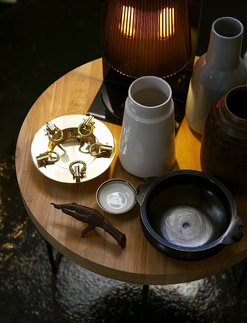 Holztisch mit Lampe, Keramikvasen und Schalen