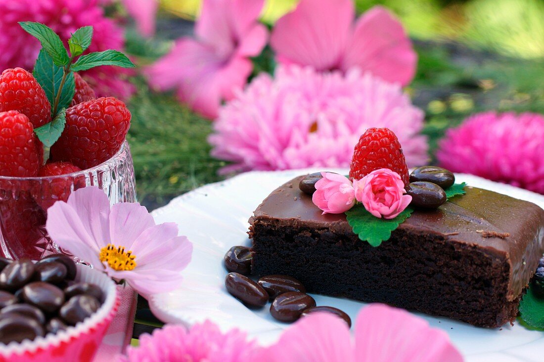 Schokoladenkuchen auf Dessertteller inmitten pinkfarbener Blütendekoration