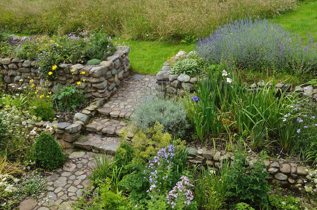 Flowering cottage garden with rough stone walls and cobbled path