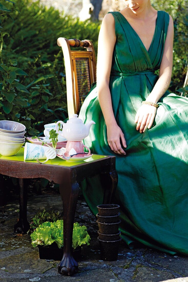 Frau sitzt im Garten zum Tee