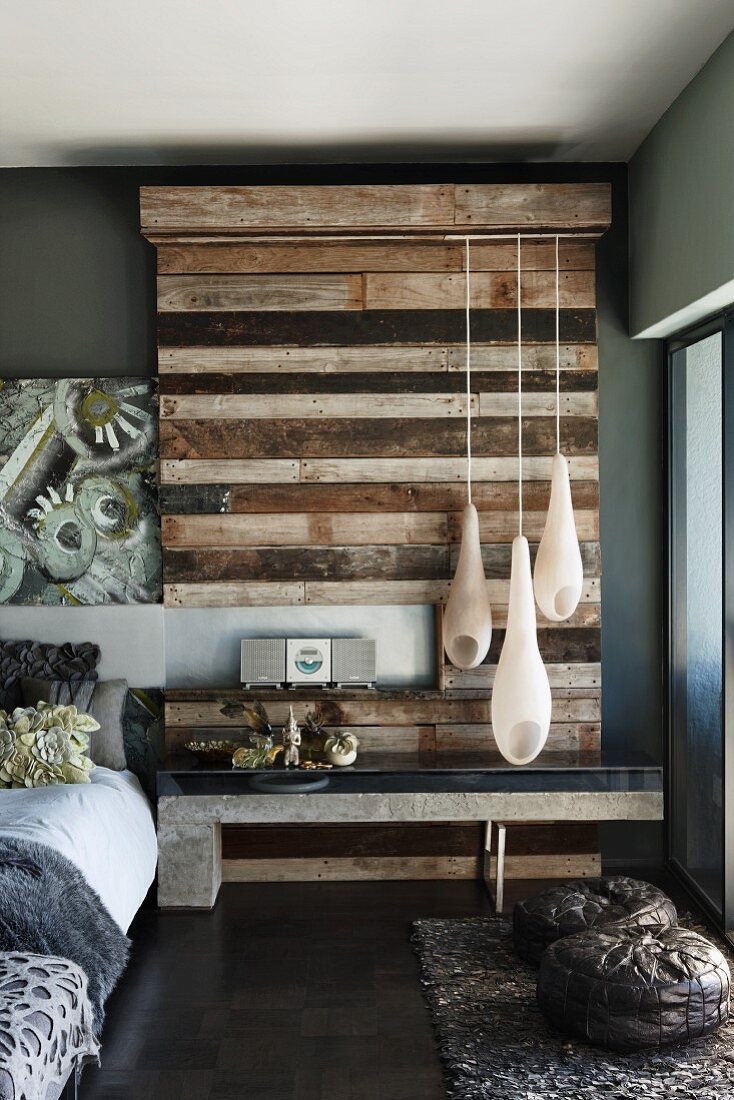 Teardrop-shaped pendant lamps in front of upcycled wood wall element in bedroom