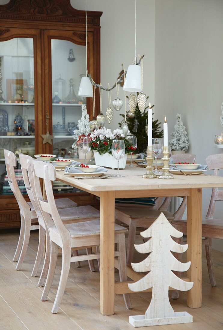 Weihnachtlich gedeckter Tisch vor einem Vitrinenschrank