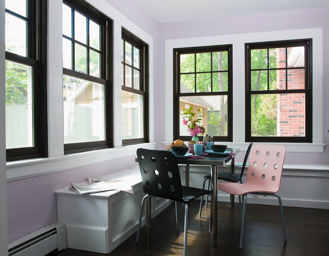 Colourful modern chairs and table in corner of room with black lattice windows