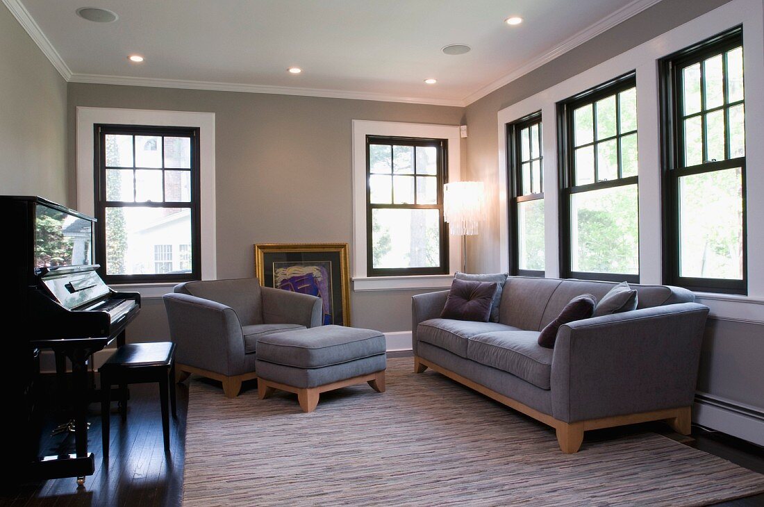 Sofa, armchair and ottoman upholstered in grey in music room with traditional atmosphere