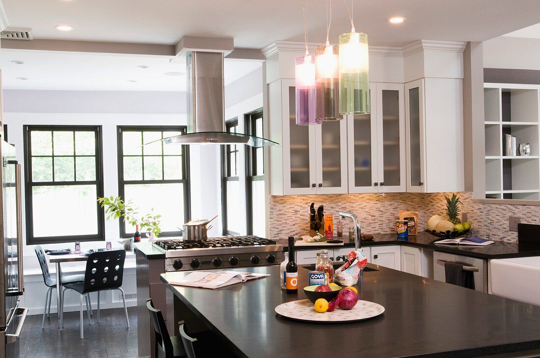 Free-standing kitchen island below modern pendant lamps with coloured glass shades