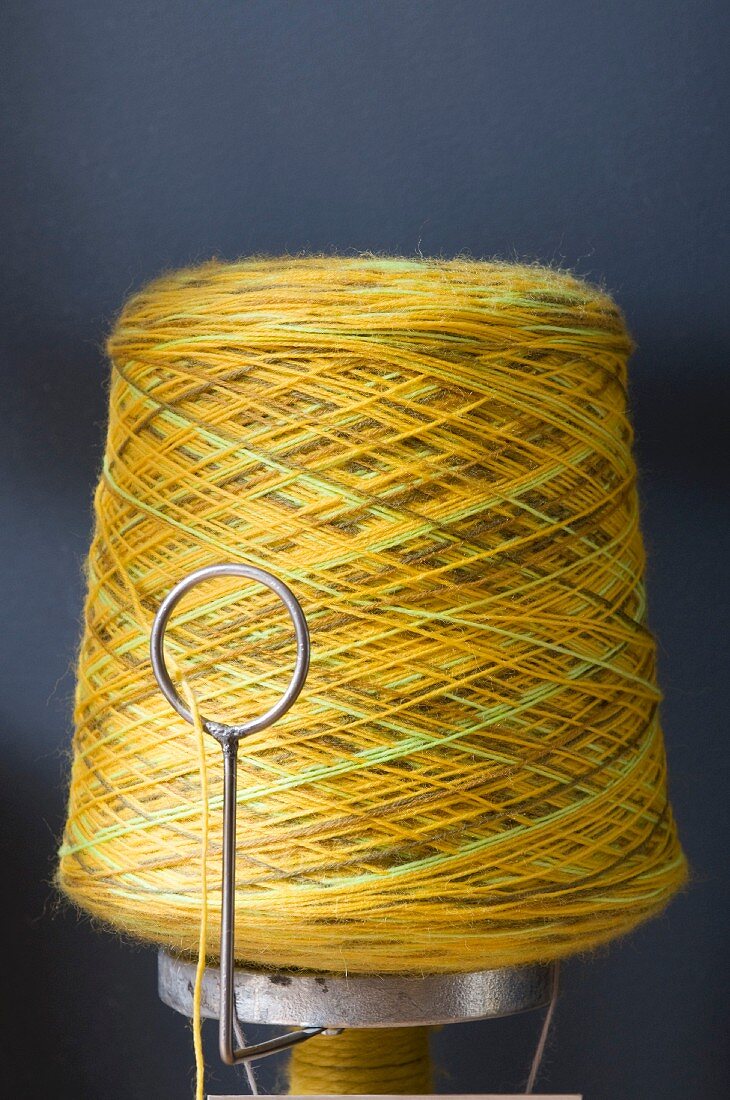 Bobbin of yellow yarn against blue background