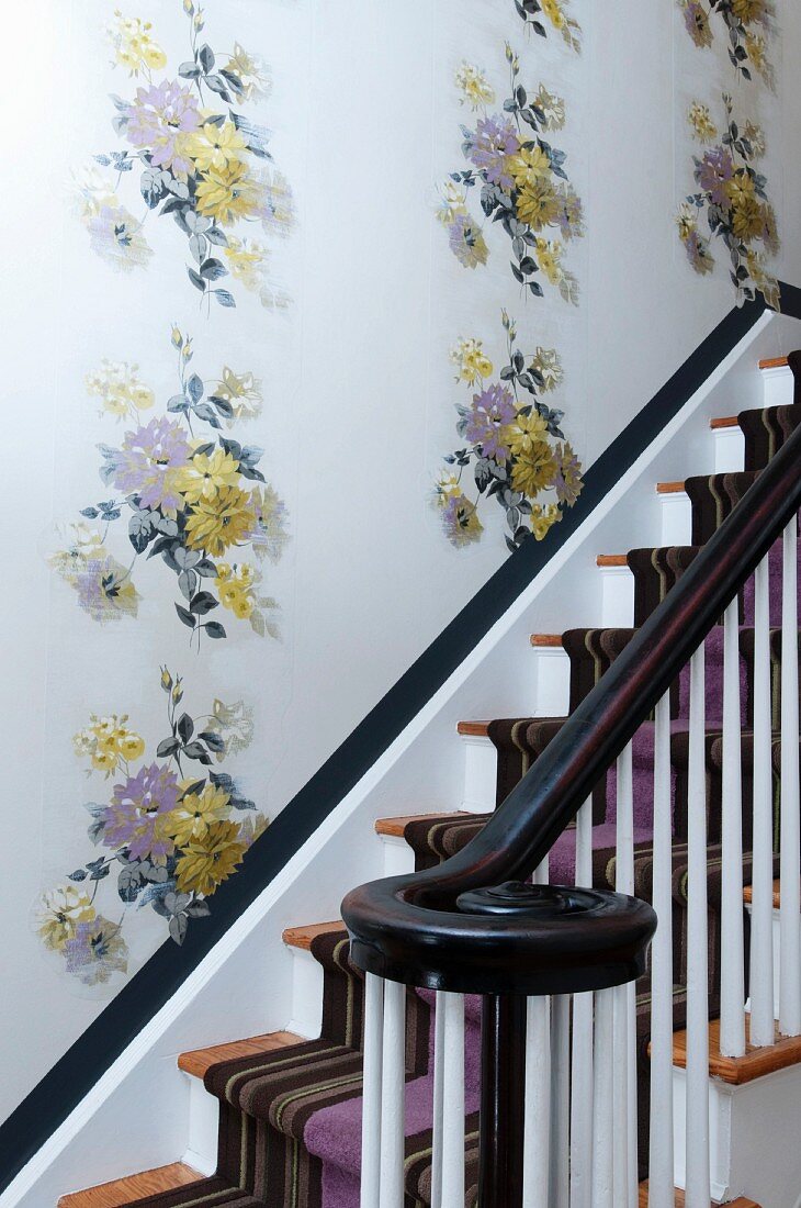 Traditional staircase with striped runner and floral wallpaper