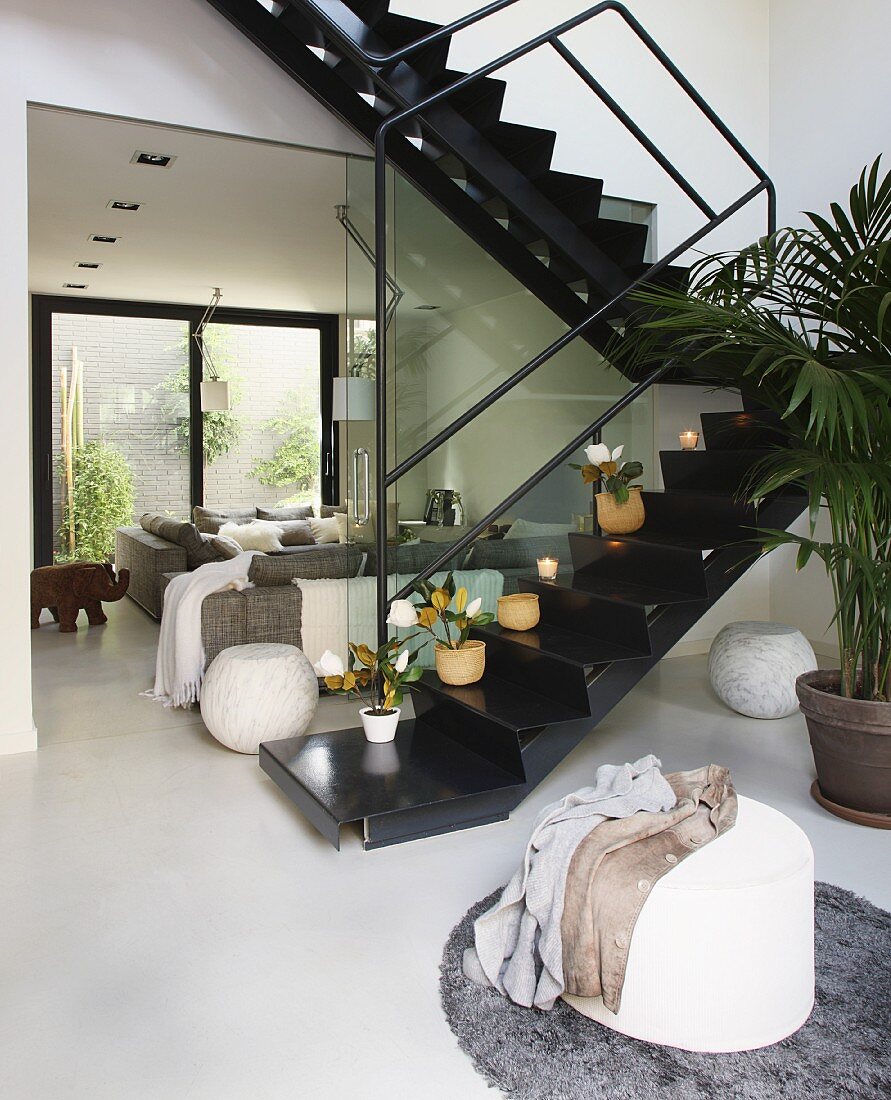 Zickzacktreppe aus schwarz lackiertem Metall im offenen Wohnraum mit Polstermöbeln in hellen, grauen Farben