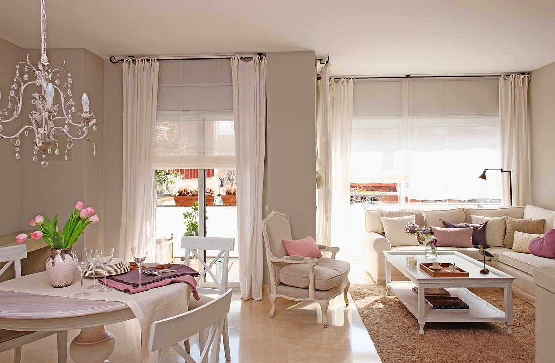 Offener Wohnraum im traditionellen Landhausstil mit Sitzecke vor Fensterfront und Essplatz mit Kronleuchter
